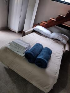 a bed with two blue pillows on top of it at Loft completo com HIDRO e piscina próx à praia in Caraguatatuba