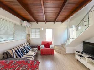 a living room with a couch and a red chair at Buzios Inn in Búzios +25 photos