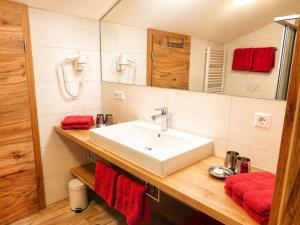 a bathroom with a white sink and red towels at Gästehaus Schönfeld in Reit im Winkl +17 photos