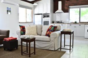 a white living room with a couch and two tables at UzuriBarossa in Altona