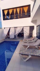 a swimming pool with two lounge chairs next to a house at VILLA KEUR BAYE FALL Saly in Sali Nianiaral