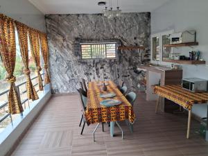 a dining room with a table and a stone wall at VILLA KEUR BAYE FALL Saly in Sali Nianiaral