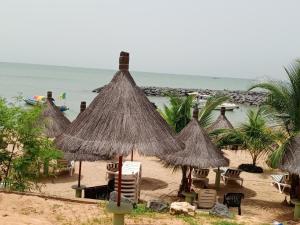 a group of straw umbrellas and chairs on a beach at VILLA KEUR BAYE FALL Saly in Sali Nianiaral