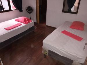 two beds in a room with red pillows on them at El Cacique in Alajuela