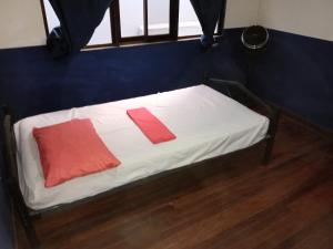 a small bed with two red pillows on it at El Cacique in Alajuela