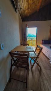 a table and chairs in a room with a bed and a window at Chalé Morada das estrelas in Aiuruoca +48 photos