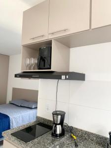 a kitchen with a counter with a microwave and a bed at Studio moderno com cozinha completa e Wi-Fi centro in Barbacena +4 photos