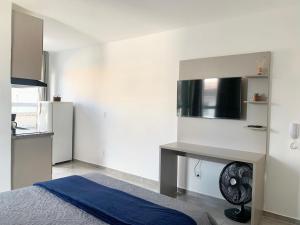 a white room with a bed and a kitchen at Studio moderno com cozinha completa e Wi-Fi centro in Barbacena