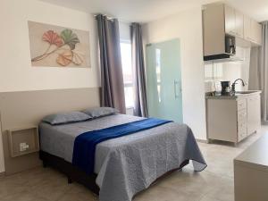 a small bedroom with a bed and a kitchen at Studio moderno com cozinha completa e Wi-Fi centro in Barbacena