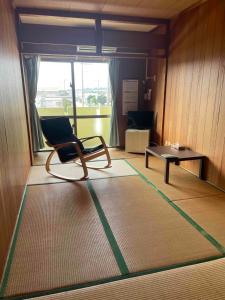 a room with a chair and a table on a rug at Adventure Hostel う島や in Iriomote