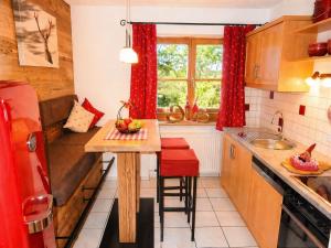 a kitchen with red curtains and a small table with red stools at Gästehaus Schönfeld in Reit im Winkl