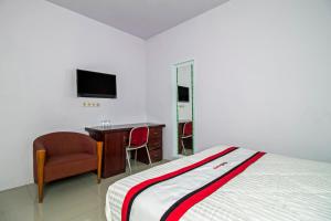 Dormitorio con cama, escritorio y TV en RedDoorz Plus @ Guntur Raya Setiabudi en Yakarta