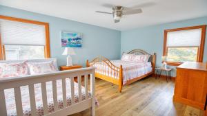 a blue bedroom with two cribs and two windows at Sunset Sands And Sea Dogs in West Cape May