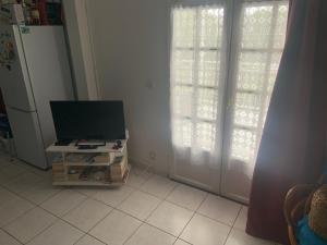 Ein Zimmer mit einem Fernseher auf einem Ständer vor einer Tür in der Unterkunft Lechampfleury in Garnier