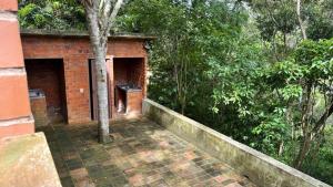a brick building with a porch in the woods at Casa no centro de Serra Negra in Bezerros