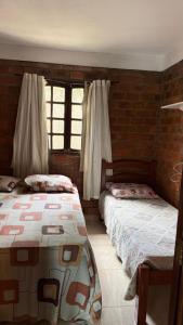 a bedroom with two beds and a brick wall at Casa no centro de Serra Negra in Bezerros