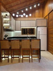 a kitchen with a counter with chairs and a refrigerator at HolzHaus em Pomerode in Pomerode