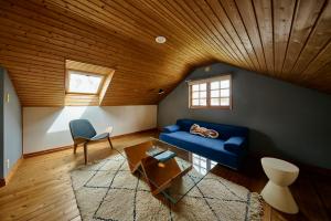 a living room with a blue couch and a wooden ceiling at Ember Resort AZUMIMO 静寂の森に佇むプライベートサウナ付き一棟貸しリトリート in Azumino