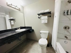 a bathroom with a toilet and a sink and a tub at Sunset Inn & Suites in Sioux Lookout