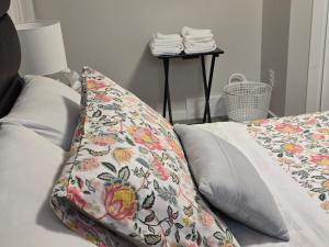 a pillow sitting on a bed with a floral blanket at The Peaceful Lower Loft in Winnipeg
