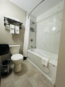 a bathroom with a tub and a toilet and a sink at Sunset Inn & Suites in Sioux Lookout