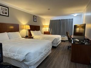 a hotel room with two beds and a television at Sunset Inn & Suites in Sioux Lookout