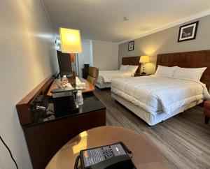 a hotel room with two beds and a desk at Sunset Inn & Suites in Sioux Lookout