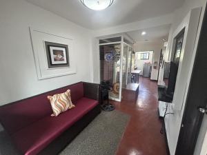 a living room with a red couch and a television at Anabelle Residence in Dumaguete