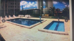 a swimming pool in a building with chairs around it at Apartamento com 02 quartos in Maceió
