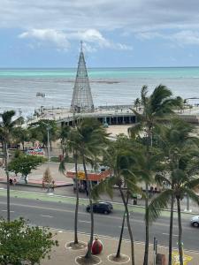 a view of a beach with a building and palm trees at Apartamento com 02 quartos in Maceió