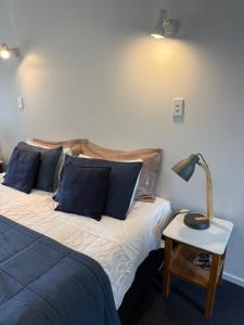 a bed with blue pillows and a lamp on a table at #5 Glenorchy Alpine Suite in Glenorchy