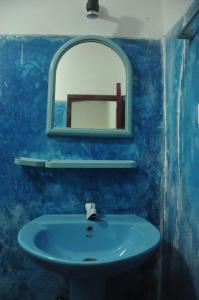 a blue bathroom with a sink and a mirror at Era Guest House in Unawatuna
