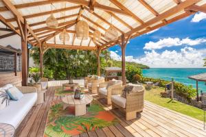 an outdoor patio with chairs and a view of the ocean at La Sirene du Diamant, villa de luxe sur la plage,18 personnes in Le Diamant