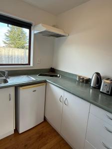 a kitchen with white cabinets and a sink and a window at #5 Glenorchy Alpine Suite in Glenorchy