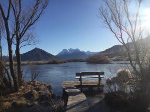 a bench sitting next to a river with mountains at #5 Glenorchy Alpine Suite in Glenorchy +3 photos