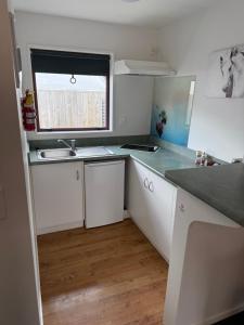 a kitchen with white cabinets and a sink and a window at #5 Glenorchy Alpine Suite in Glenorchy