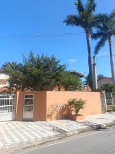 a orange building with palm trees and a fence at Sool Beach Hostel in Bertioga