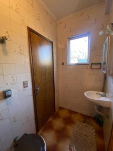 a bathroom with a toilet and a sink and a door at Sool Beach Hostel in Bertioga