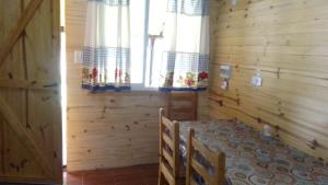 a wooden room with a bed and two windows at Cabañas del Valle in Huerta Grande