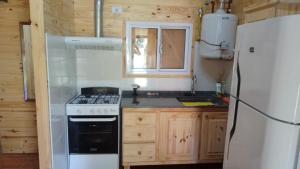 a kitchen with a white stove and a refrigerator at Cabañas del Valle in Huerta Grande