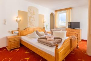 um quarto com uma cama com lençóis brancos e uma televisão em Sterzinger Posthotel em Nassereith