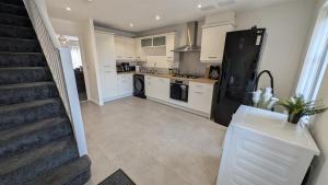 a kitchen with white cabinets and a black refrigerator at Large Modern House With Private Parking in Heeley