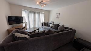 a living room with a brown couch and a tv at Large Modern House With Private Parking in Heeley