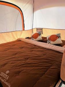 a bed in a tent with two pillows on it at KhaoSok Malin Glamping in Ban Bang Thong