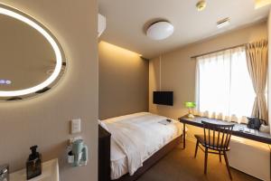 a bedroom with a bed and a desk and a mirror at Business Hotel Hayashiso in Miyazaki
