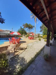 a patio with tables and chairs next to a pool at Recanto Praia Peruibe in Peruíbe