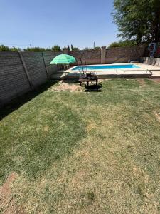 a yard with a table and an umbrella next to a swimming pool at Los Girasoles in Albardón
