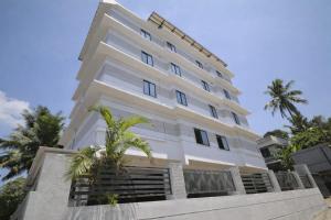 a white building with palm trees in front of it at Tara inn in Alwaye