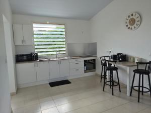 a kitchen with white cabinets and a table with stools at Bella - Destination Guyane in Rémire-Camp