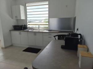 a kitchen with white cabinets and a table and a window at Bella - Destination Guyane in Rémire-Camp +11 photos